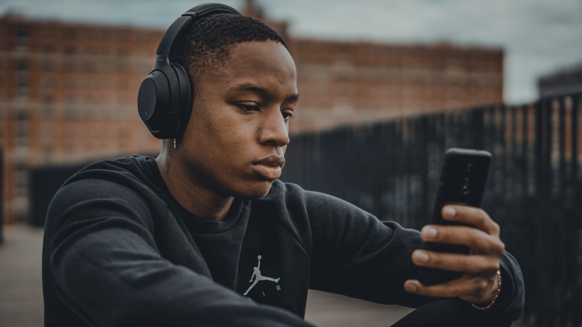 A guy listening to music while looking at his phone
